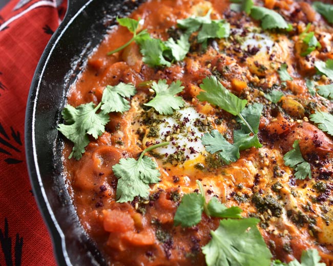 Partial view of cast iron pan showing za'atar and sumac on egg tomato mixture.