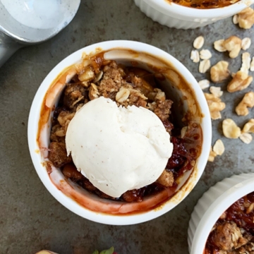 face down view of fruit crisp with ice cream in small white bowls