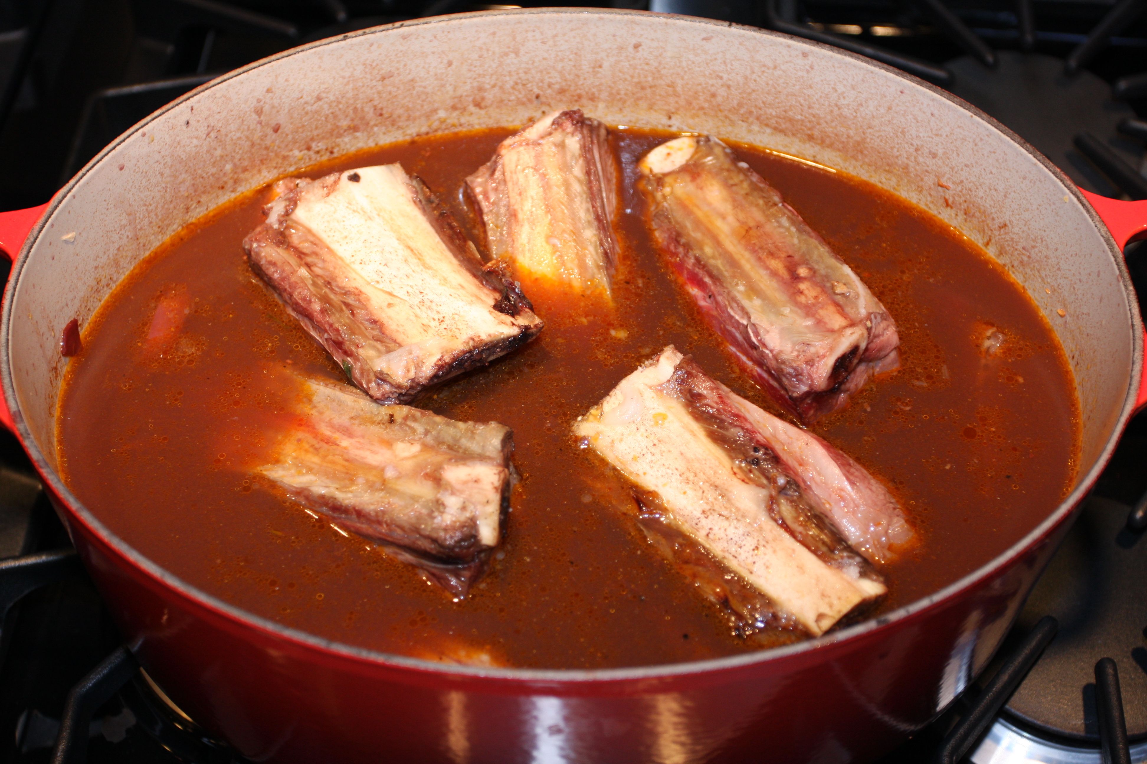 Dutch oven with short ribs in sauce.