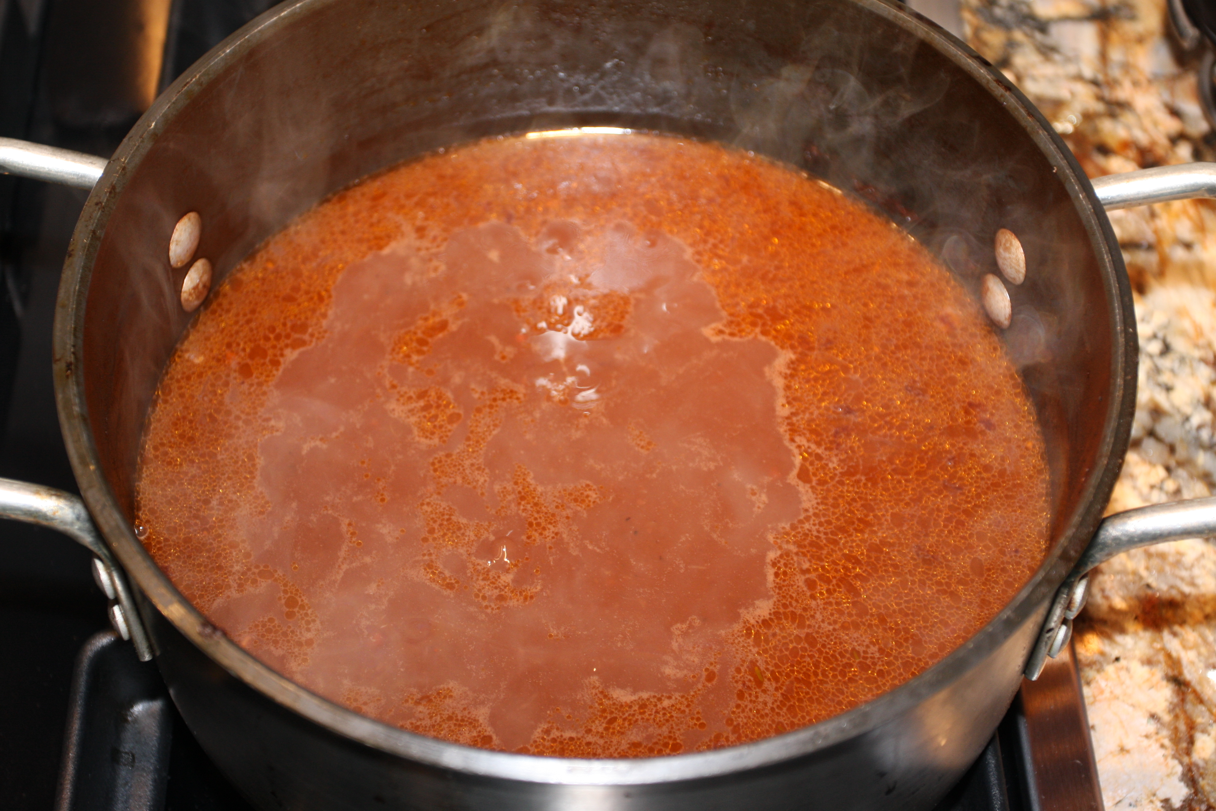 Saucepan with sauce reduction on stovetop.