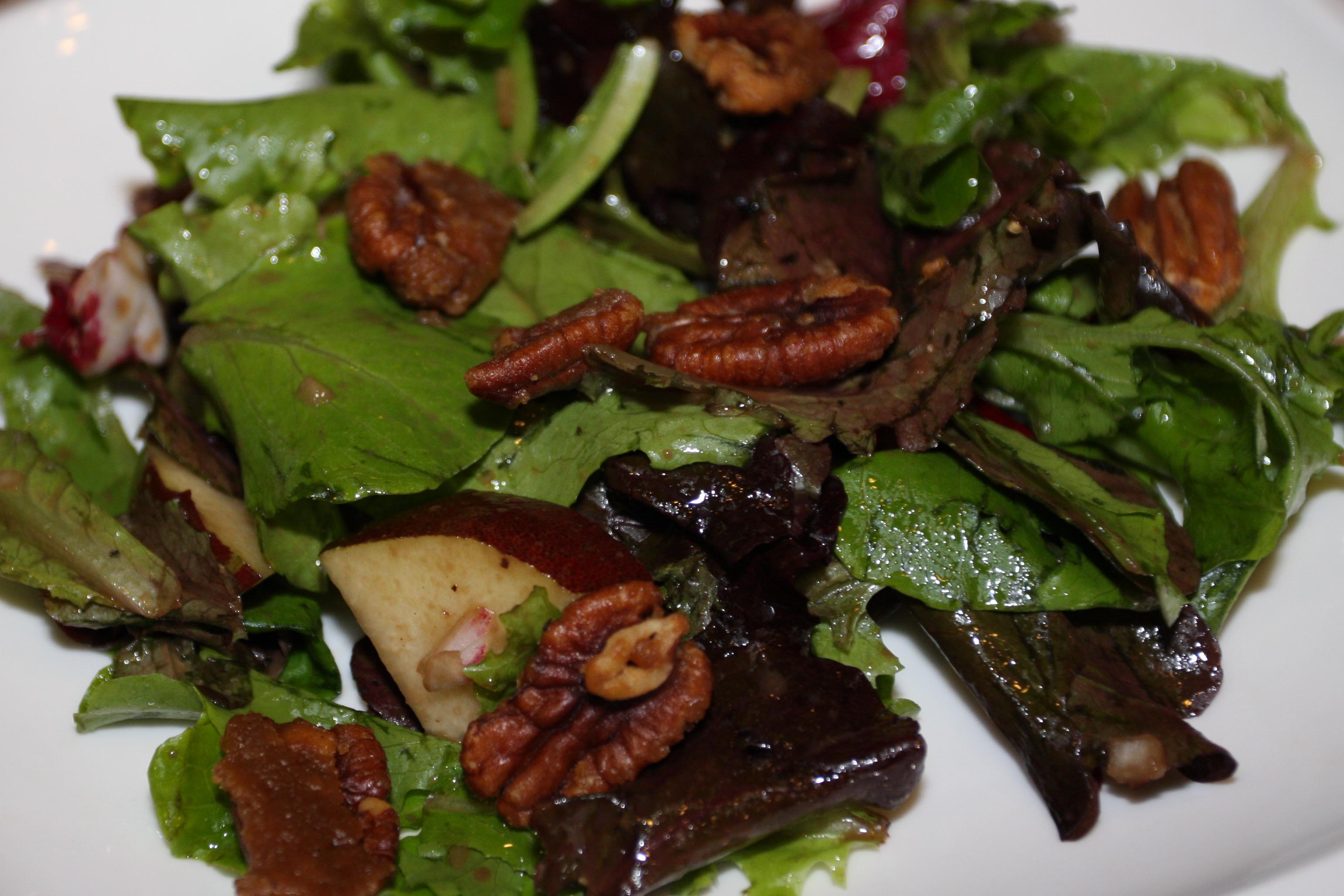 Fall salad on a white plate with pecans.