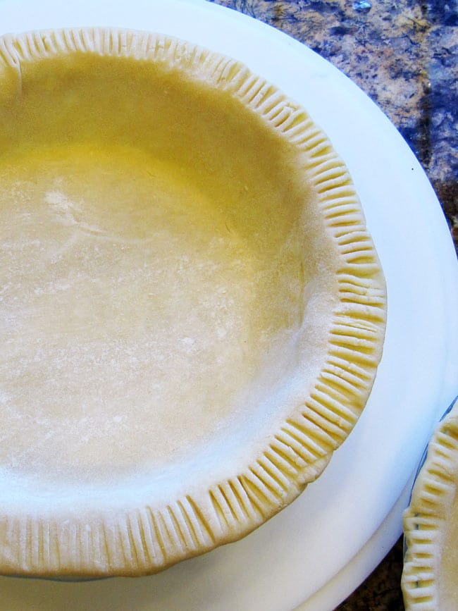 Raw pie dough in a pie pan on cutting board.