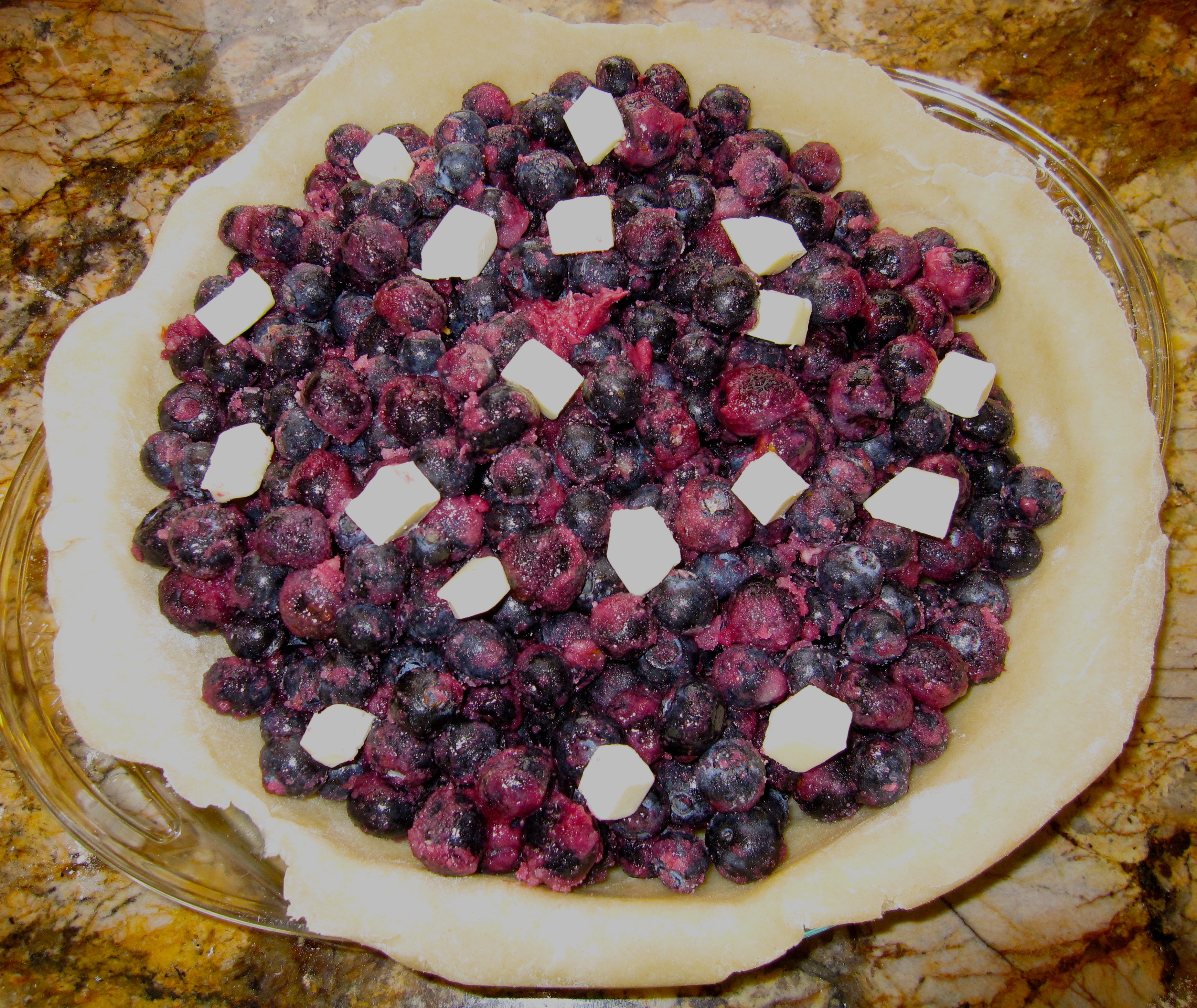 Blueberries and butter in unbaked pie shell.