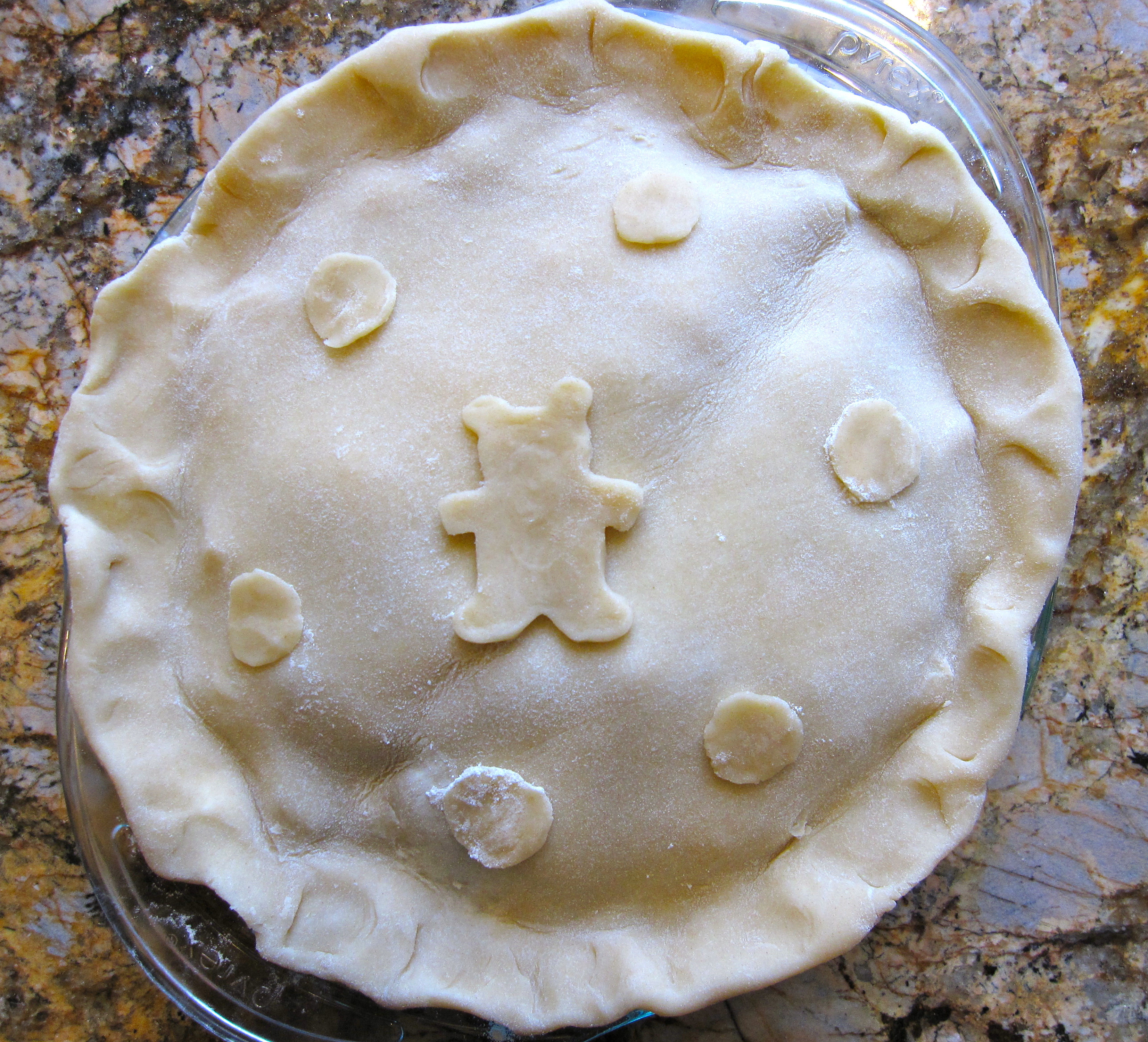 PIe topped with crust with decorative pie crust pieces in shape of a bear and circles.