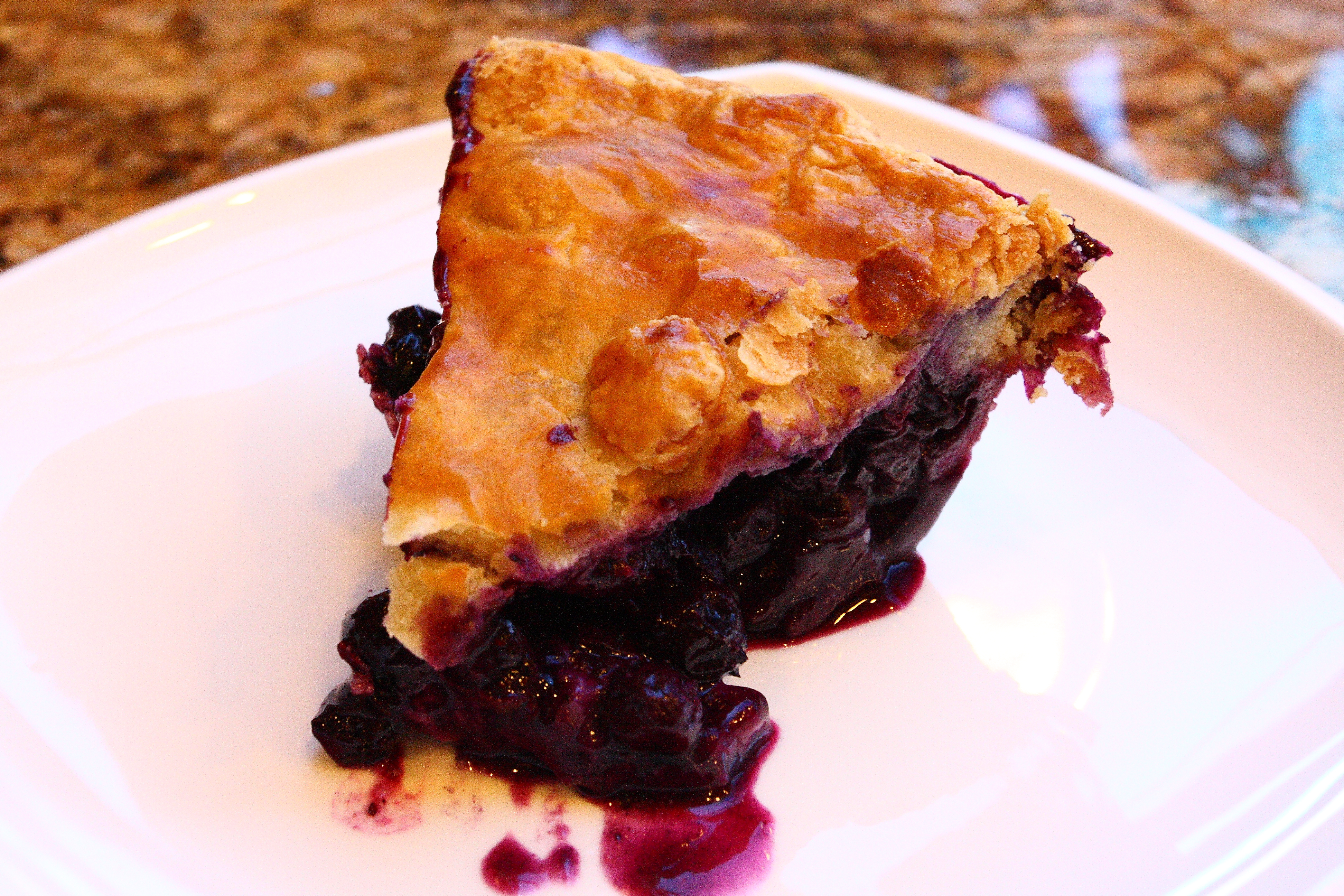 A slice of blueberry pie on a white plate.