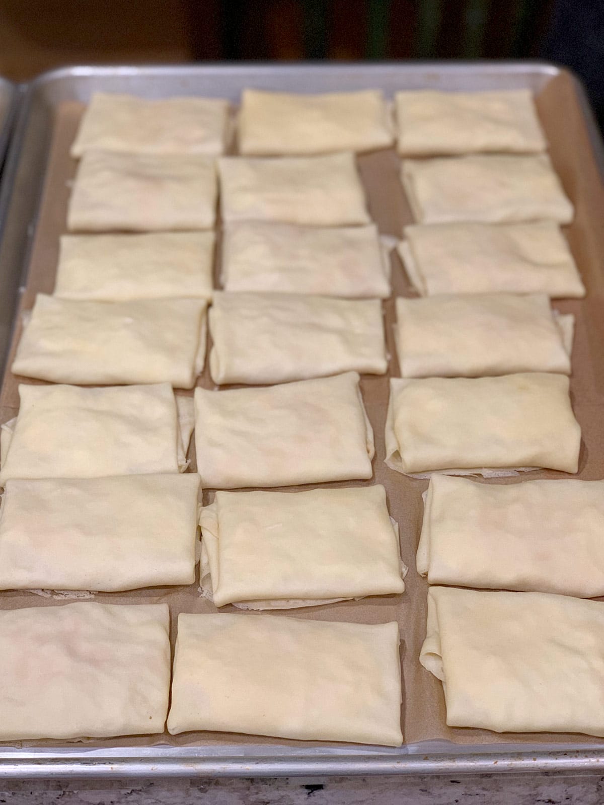 A tray of Sharon's blintzes on parchment, ready to be cooked.