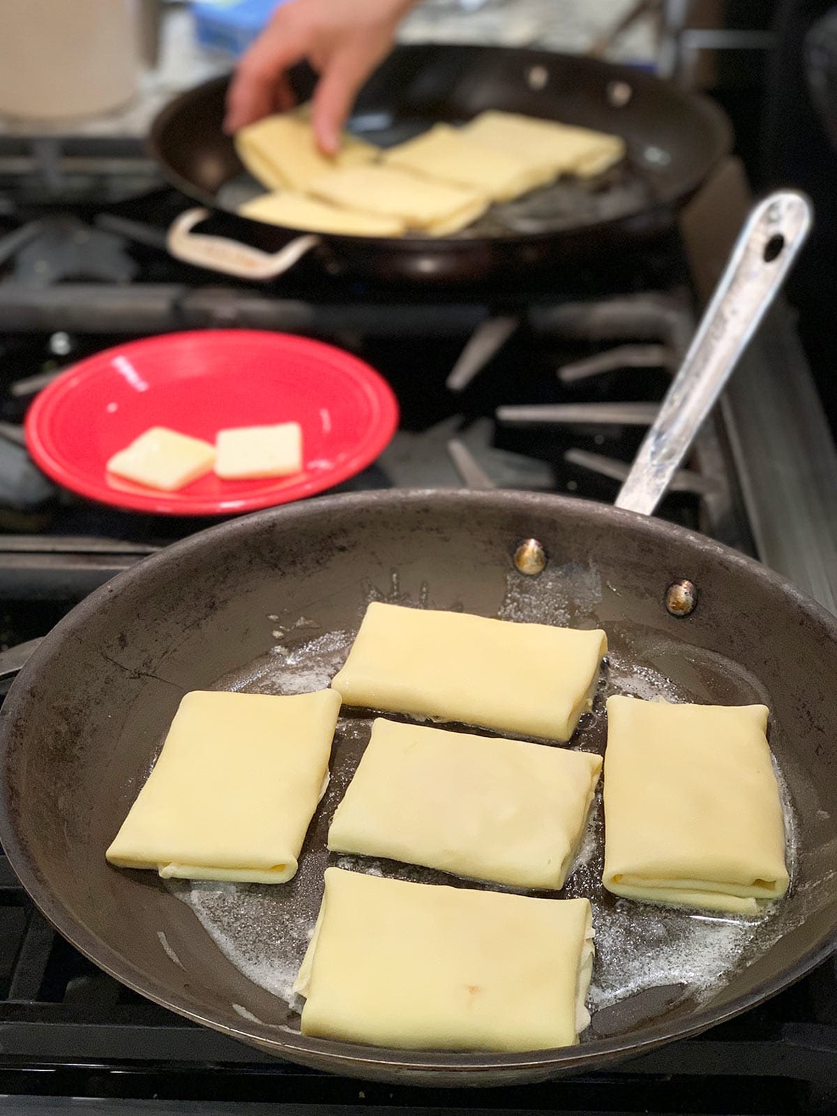 Several blintzes cooking in large pan on stove.