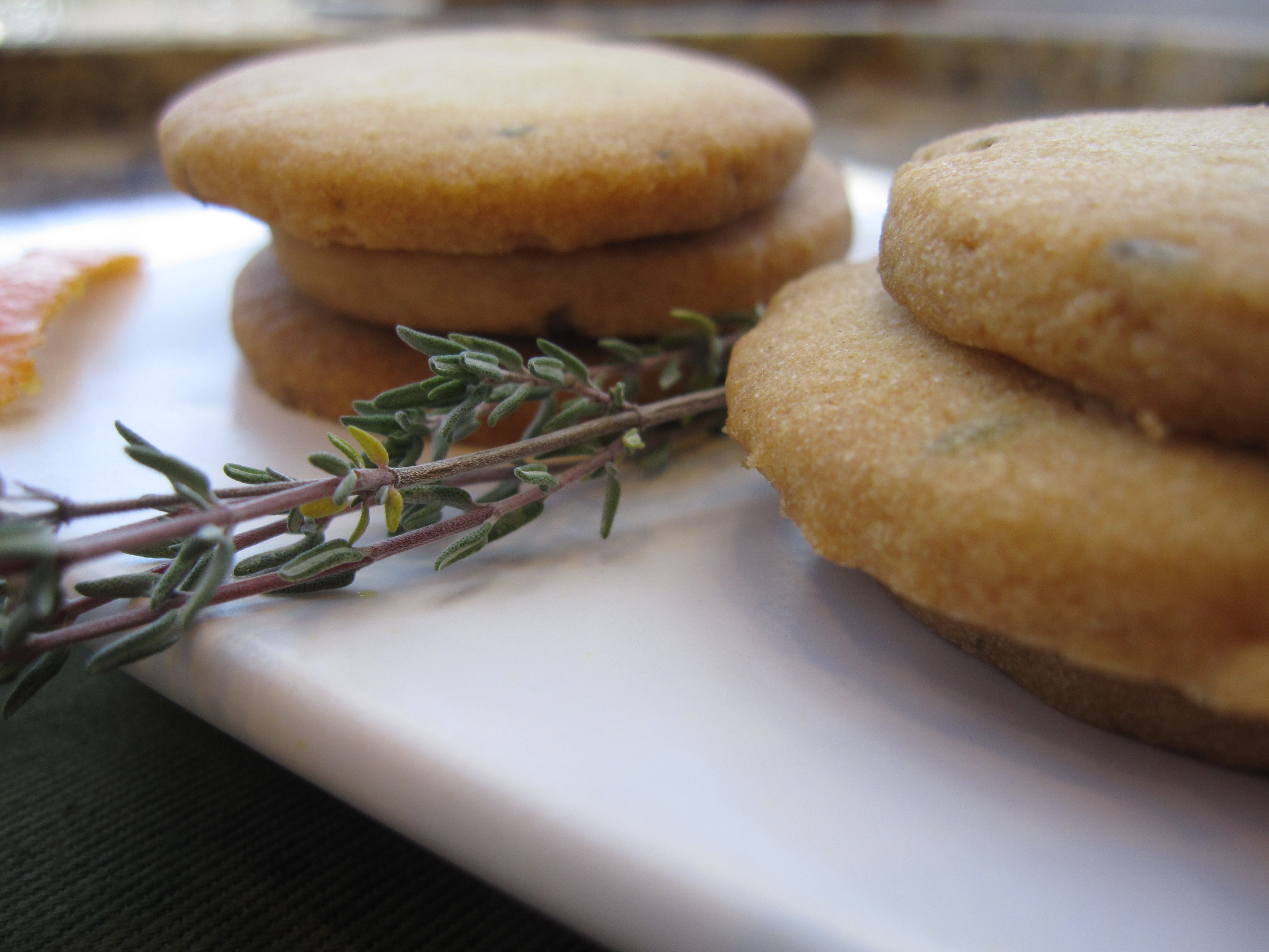 Orange Thyme Cocktail Cookies on a white platter with fresh thyme garnish.