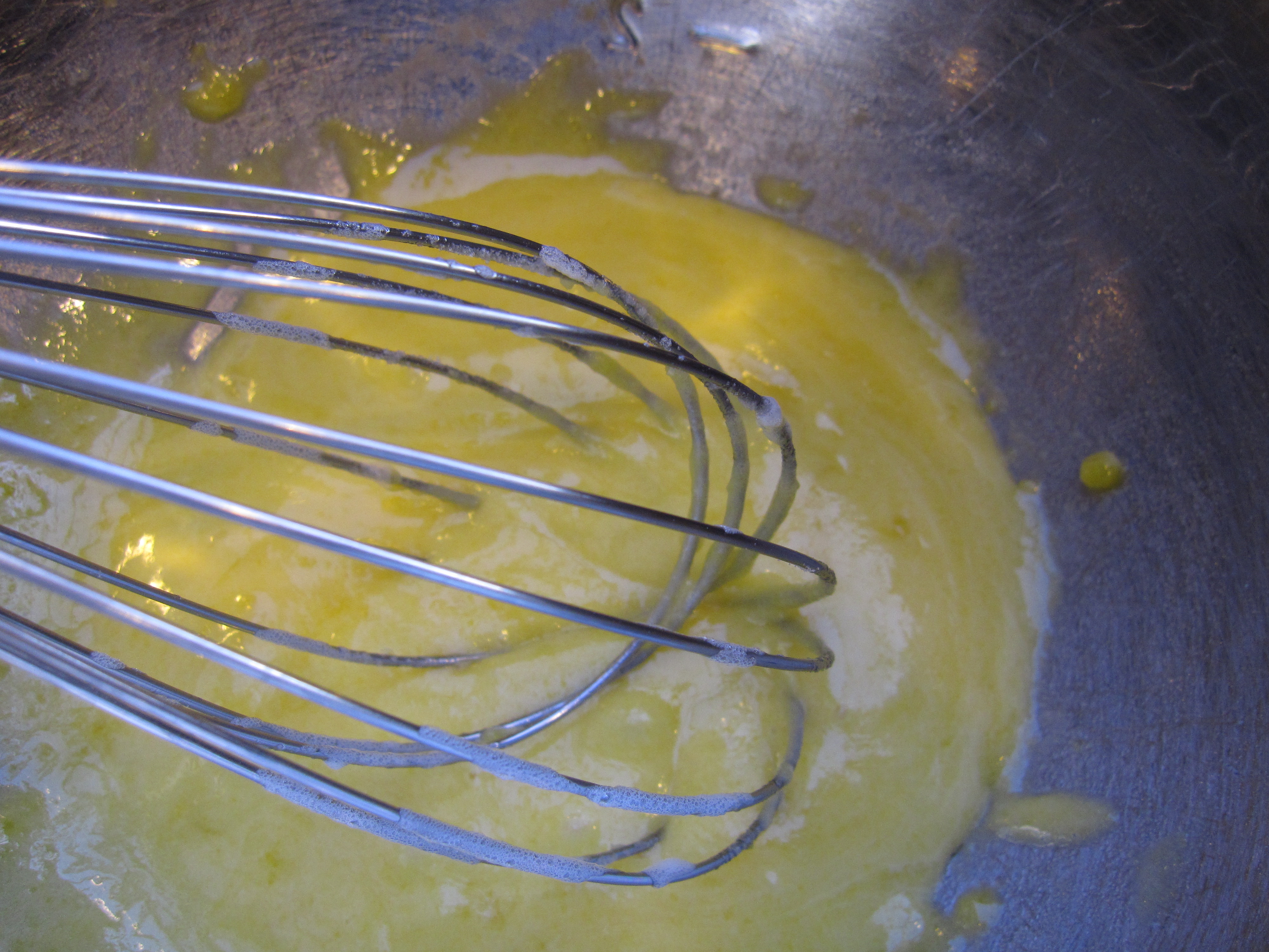 egg yolks being beaten with a wire whisk.