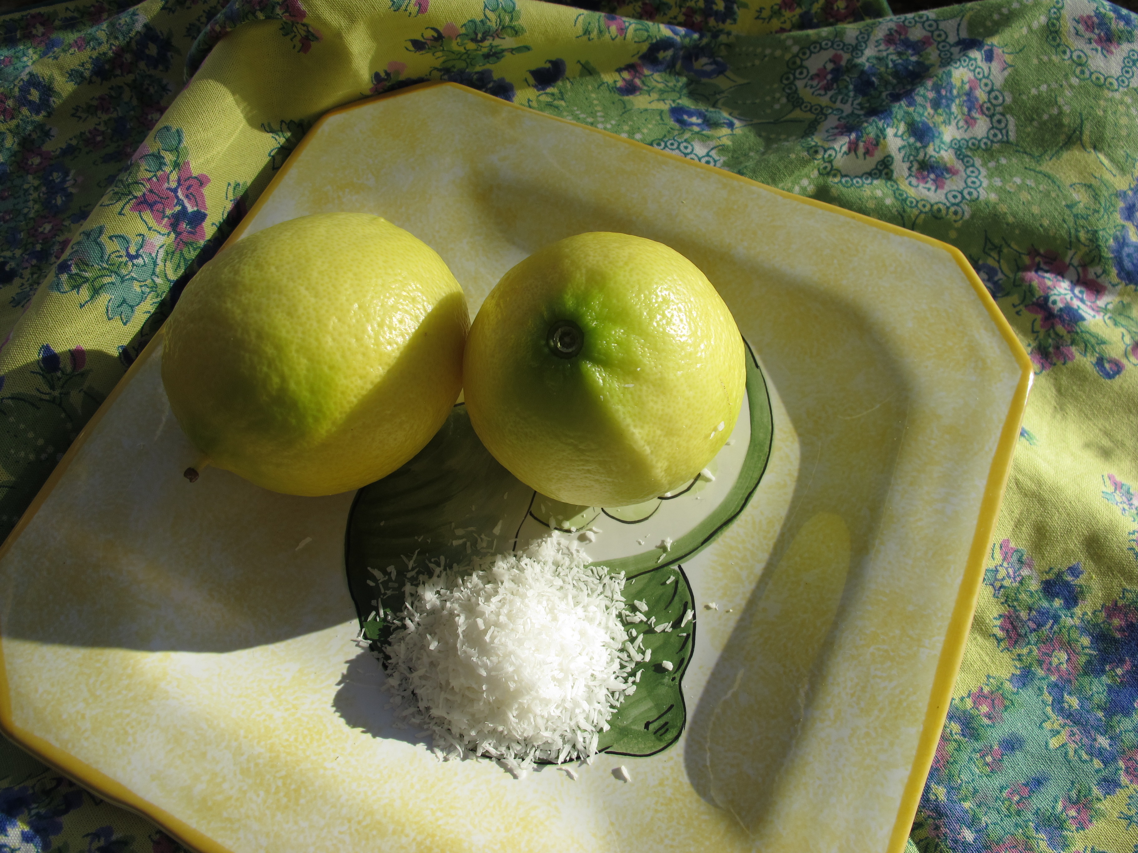 yellow and green limes on a yellow plate with shredded coconut.