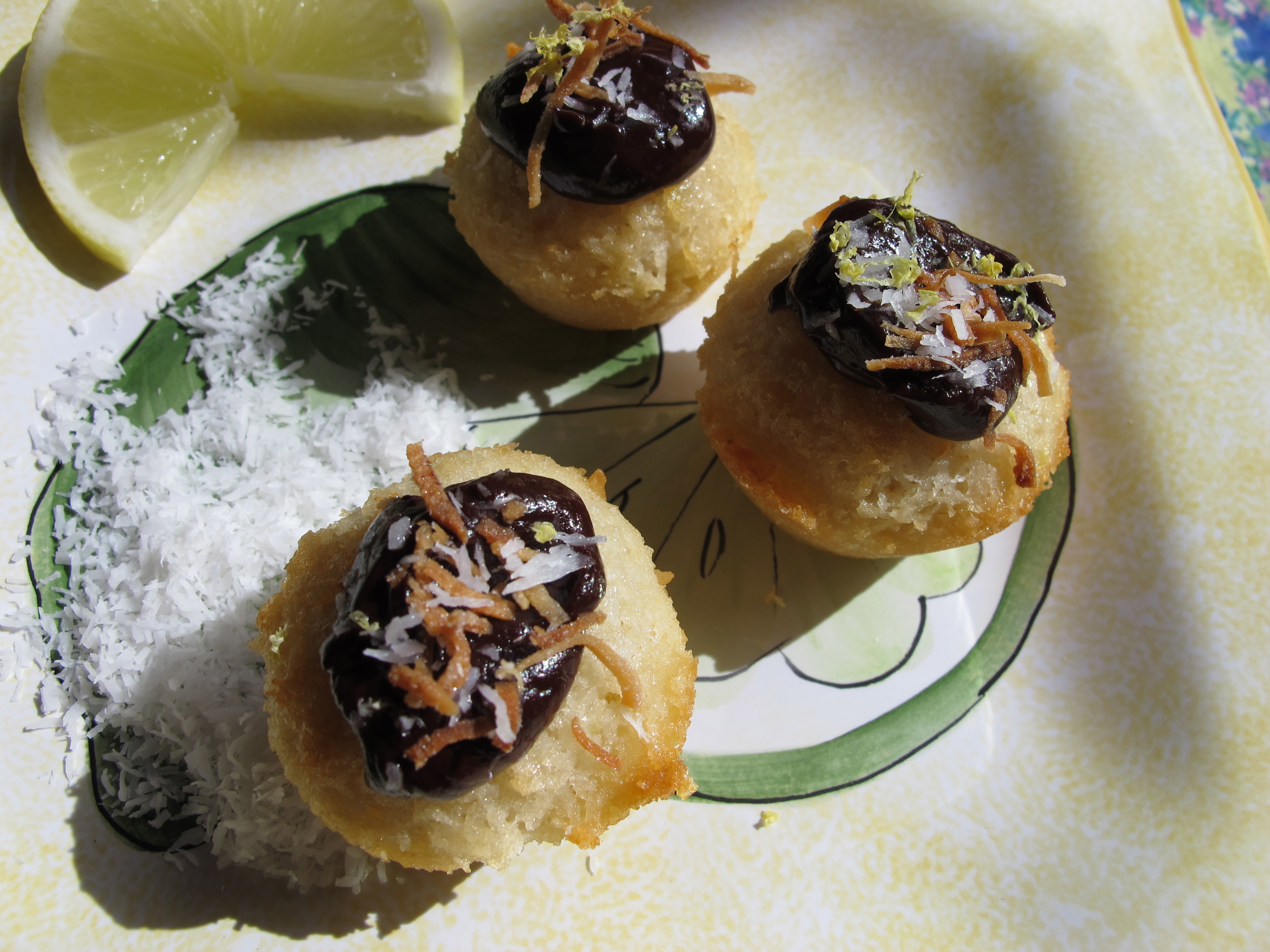 3 friands on a plate with shredded coconut and a slice of lime.