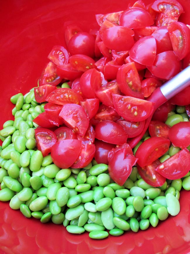 tomatoes and edamame in red bowl with red spoon