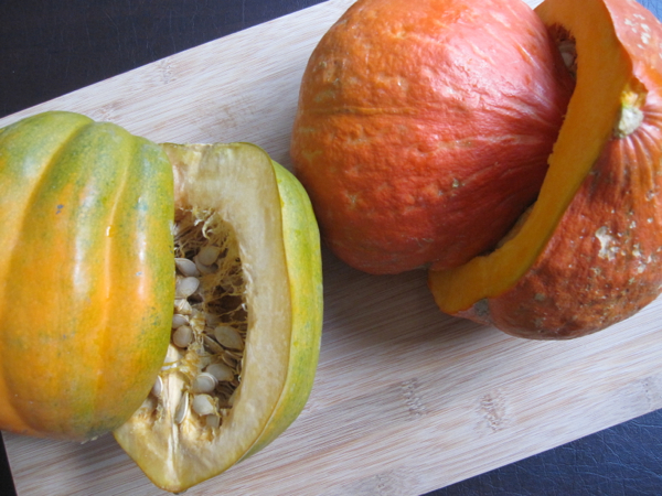 A yellow and orange skinned squash both cut open showing their flesh and seeds.
