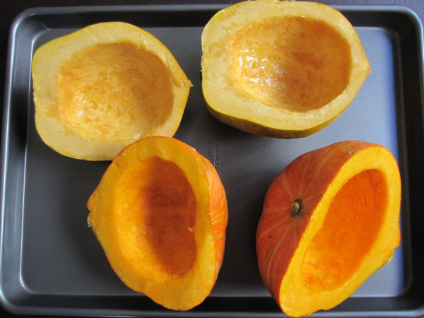 Squash halves cleaned of seeds on a baking tray ready for the oven.