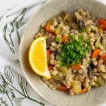 pinterest image with barley soup in bowl with lemon