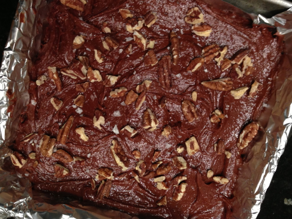 A square baking pan lined with foil containing batter for mocha brownies ready to bake.