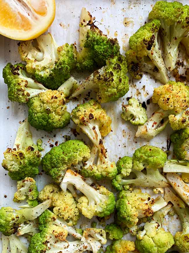 Roasted green cauliflower on parchment with lemon.