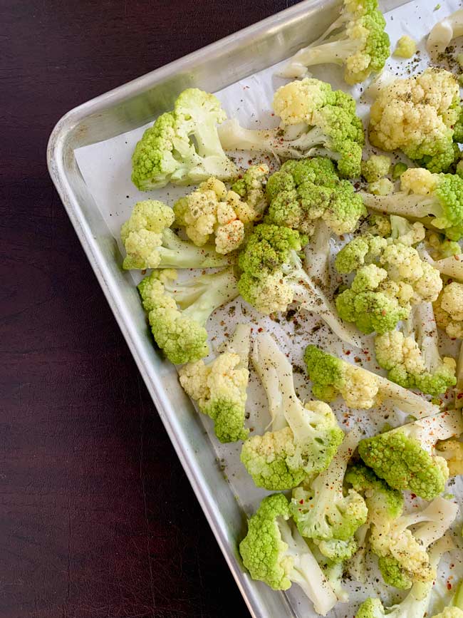 Green cauliflower on tray cut into florets, ready for the oven.