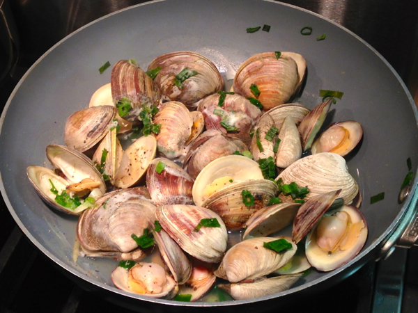 Using a  wok style pan, making sake steamed clams.