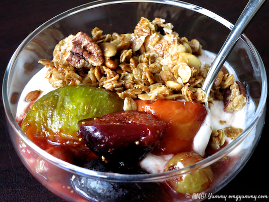 Roasted fruit with pomegranate molasses in a dessert dish with yogurt and granola, ready for serving.