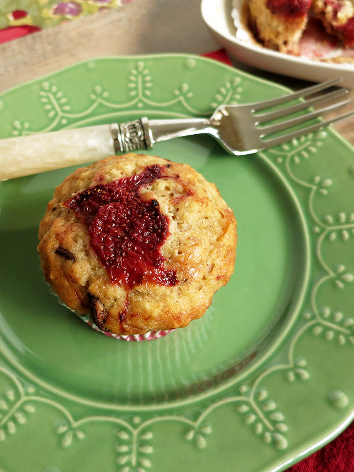 Roasted strawberry muffin on a green plate with a fork and another muffin on a white plate in the background.