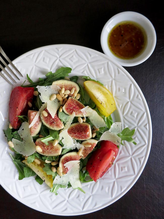 fork tines on white bowl of salad with dressing in upper right in small white bowl