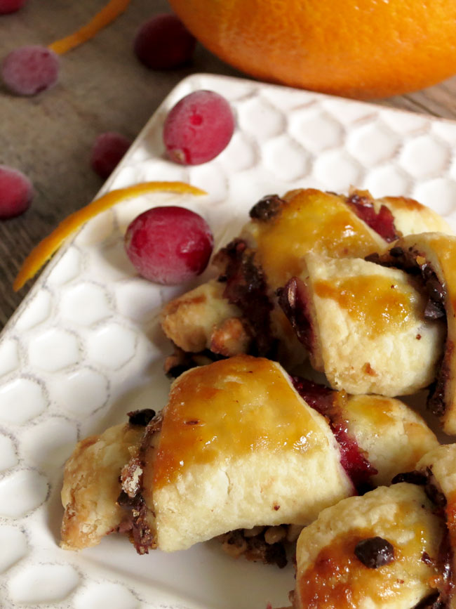 Close up of orange cranberry rugelach on a white plate.