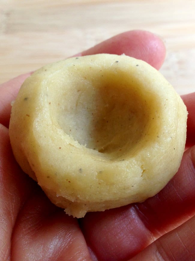 One date thumbprint cookie dough in hand showing indentation.