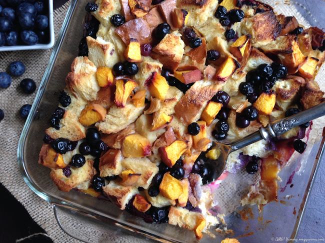 Baked bread pudding with a serving missing and a serving spoon.