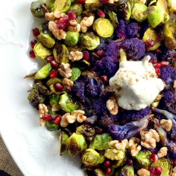 roasted brussels sprouts with yogurt topping and purple cauliflower on a white plate