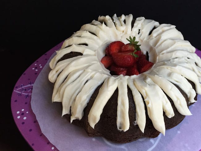 A Chocolate Lover's Chocolate Bundt Cake with Cream Cheese Frosting and fresh strawberries in the middle.