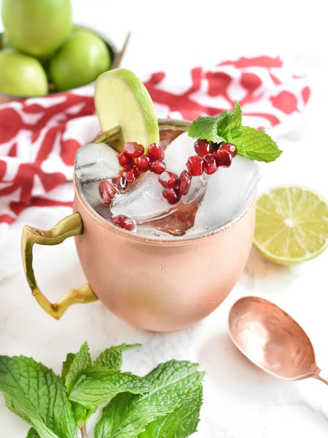 pomegranate molasses cocktail in a copper mug w limes and mint