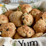 Irish soda biscuits in a basket with a napkin that says yum and a cooling rack in the background.