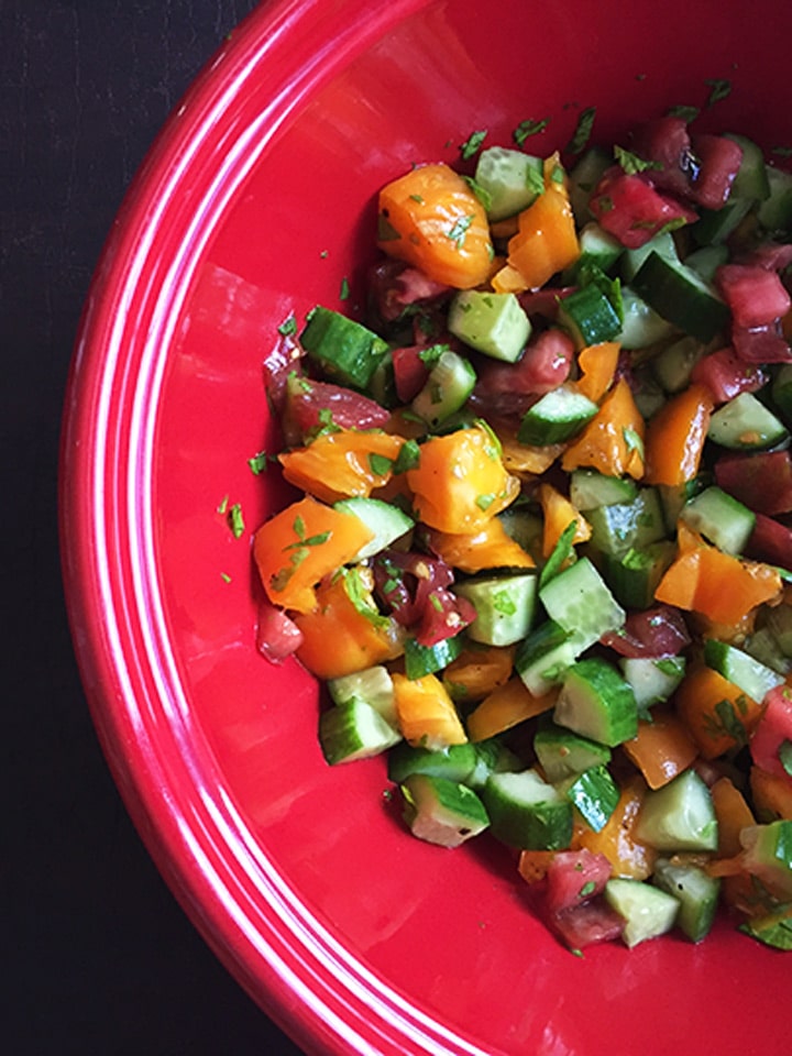 Cucumber tomato salad in a red bowl.