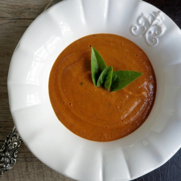 shot of roasted tomato sauce in white bowl with basil sprigs on top