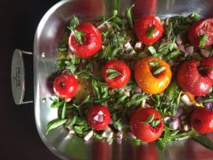 tomatoes pre-roasting in pan with herbs face down view