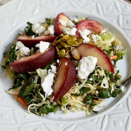 Quinoa and nectarine slaw in a white salad bowl with a lemon napkin in the background.