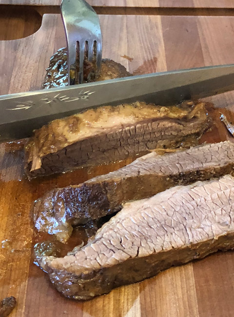 Instant Pot Brisket slicing cooked meat on board to show grain.