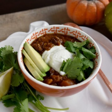 Instant Pot Red Lentil Chili in a bowl at an angle with avocado, cilantro and yogurt on top