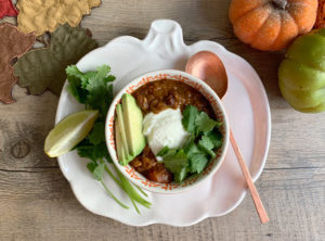 Instant Pot Red Lentil Chili with Pumpkin and Black Beans top down beauty shot with orange bowl on pumpkin plate