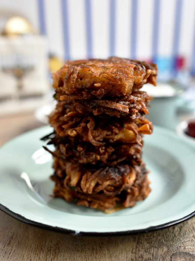 stack of latkes with hanukkiah in the background