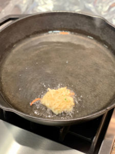 testing one latke to cook in oil in cast iron pan