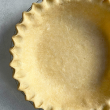 Pie crust in a pie pan with a fluted edge.