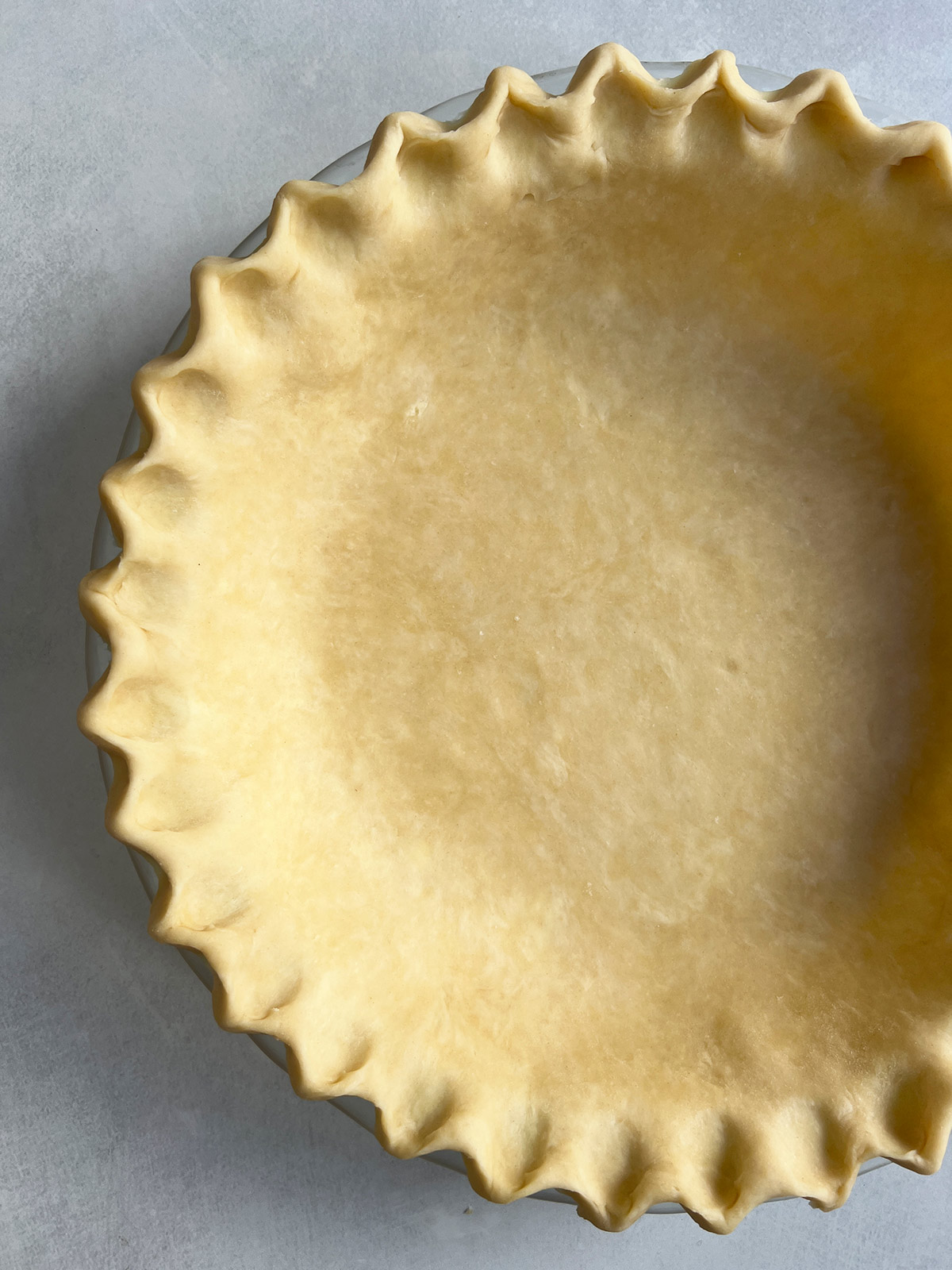 Pie crust in a pie pan with a fluted edge.