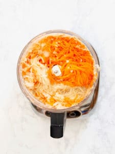 shredded carrots and potatoes in food processor for potato kugel