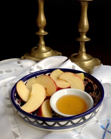 apple honey in bowl with candlesticks in background