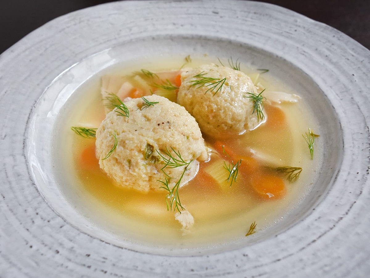 Matzo Ball soup in a white bowl at an angle.