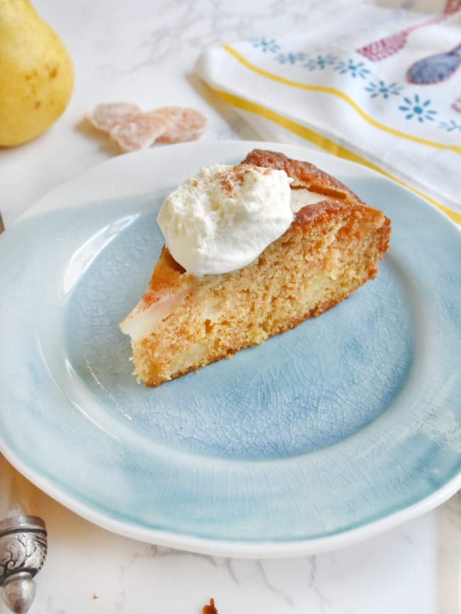 A slice of pear cake with whipped cream on blue plate.