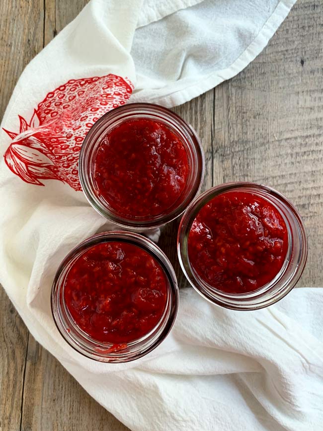 3 jars of jam with white napkin and wood background.