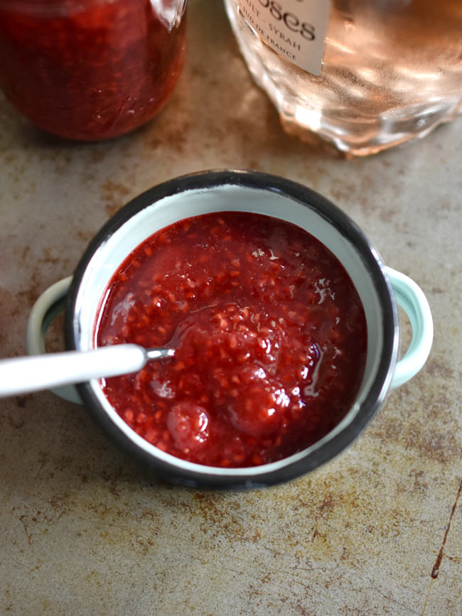 Strawberry Raspberry jam w spoon on old tray with wine bottle.